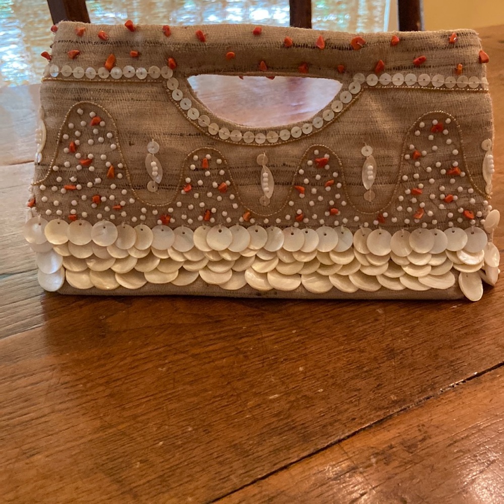Beautiful seashell and beaded clutch on tan burlap linen background